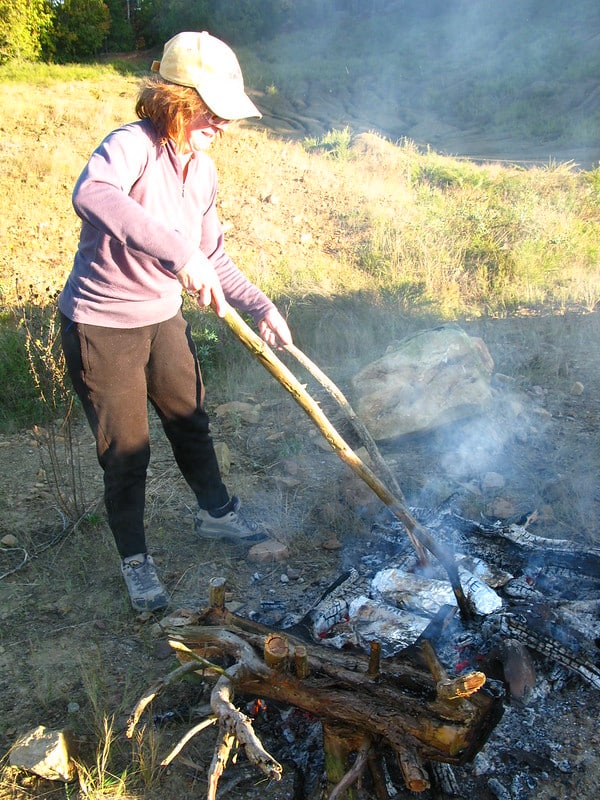 using sticks to turn food over campfire