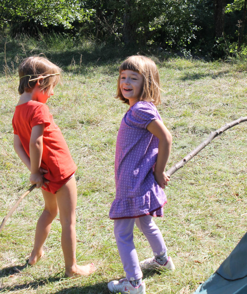 kids playing with sticks while camping