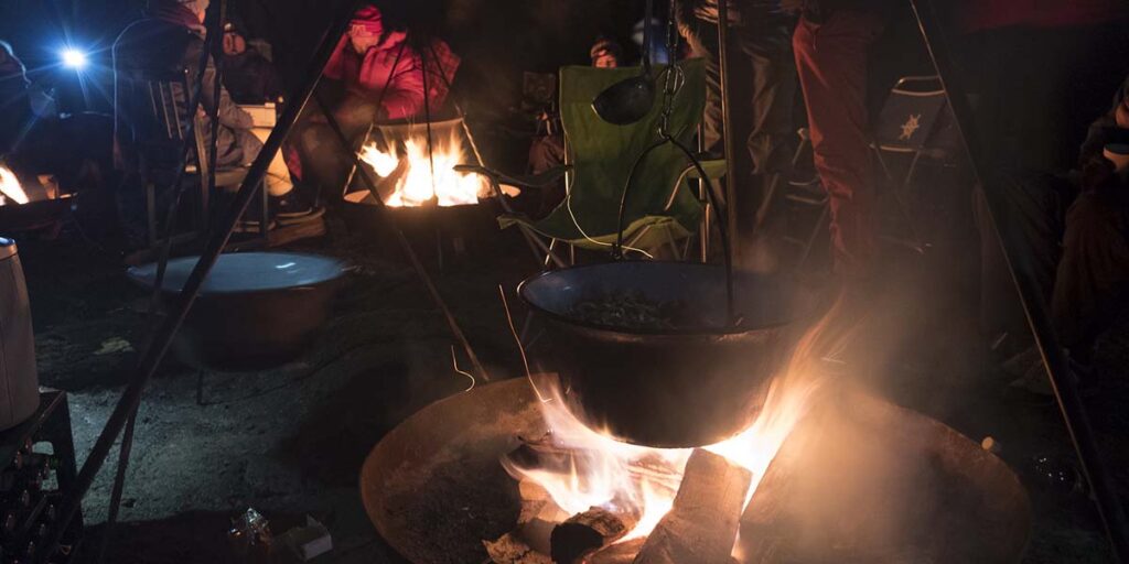 cooking over a campfire with a tripod